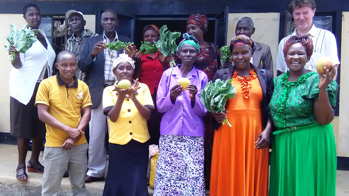A group of leaders from the Makakya Community-based Organisation (CBO) showing off their crops (with ABM's Effectiveness and Learning Coordinator Terry Russell).