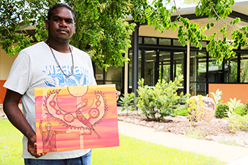 Aboriginal Artist and Nungalinya College Christian Ministry and Theology student, Troy Mardigan, holds his powerful artwork, Creation Story.