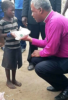 Archbishop Thabo Makgoba of the Anglican Church of Southern Africa presents a child with a food parcel following Cyclone Idai.