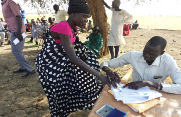 Beneficiary in Aruch Boma, Jamjang Payam signing for her money (source: ACT Alliance)