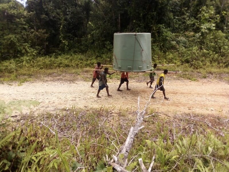 Youths carry a tank from the shore to the local primary school. Photo credit: Albert Aisim, Anglican Church of Papua New Guinea. Used with permission.