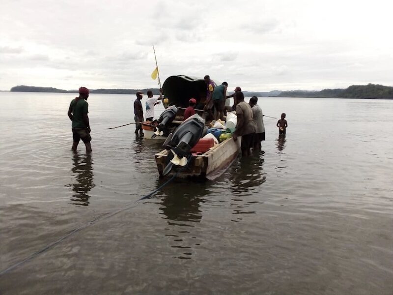 Local volunteers offload a Tuffa tank from dugout canoe to dinghy, to be transported to the village on foot. Photo credit: Albert Aisim, Anglican Church of Papua New Guinea. Used with permission.