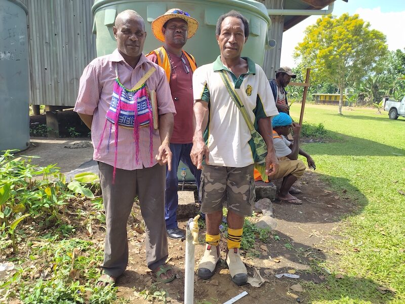 Diocese of New Guinea Islands’ Project Officer, Isaac Nagiring, stands with a primary school head teacher and treasurer in front of a newly-installed water tank at a West New Britain school.