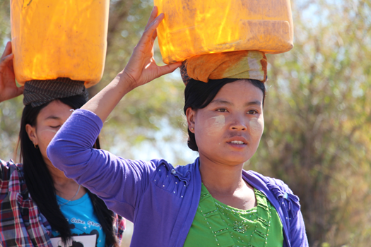 Women in Pyay Deanery carry containers after collecting water. © Brad Chapman/ABM, 2015.
