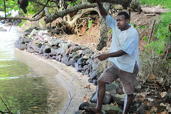 Fr Ben Gislapwos explains how a wall was built to stem the rising sea water at Port Patteson on Vanua Lava, Vanuatu.