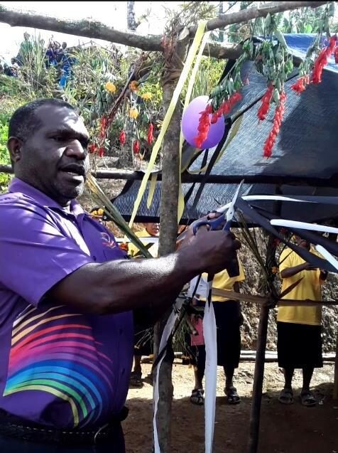 Anglicare PNG Mt Hagen Branch Manager, Ruben Fuafo, cut the ribbon to open a new Adult Literacy Classroom made from Kunai leaves.