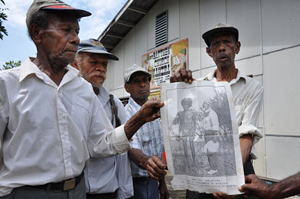 proudly recalling the arrival of the first missionaries these men from Wamira hold a photograph.