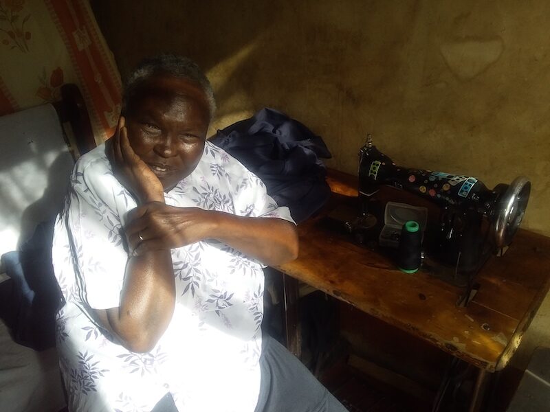 Julie with her old sewing machine before she replaced it with a new one, purchased from her project loan.