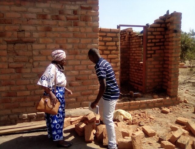 ZACOP’s Country Director, Mrs Felicia Sakala, talks with Selemani about the opportunities the project has given him, as he builds his house. © ZACOP. Used with permission.