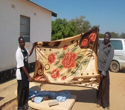 A staff member and Headman at Chishinka show off blankets and bedding.