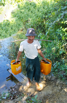 A man draws water from the local pond. © Julianne Stewart/ABM, 2015.