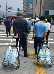 Clergy from the Diocese of Seoul supply water for hunger strikers hoping for justice for the young victims of the Sowol ferry disaster.