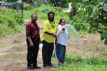 Acting Deputy Principal (left), Peter Usumae and wife Anna show water coming from the bore hole.