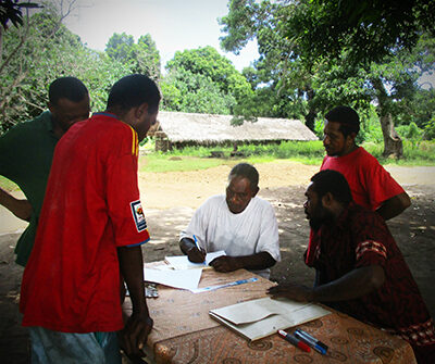 Fr Nicholson Worek drawing a map with community members for WASH Vanuatu. © ACOM 2017. Used with permission.